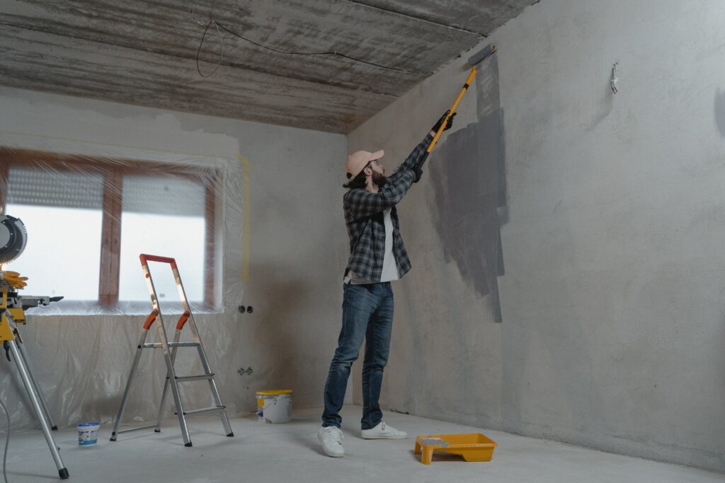 man painting a room with roller and step ladder