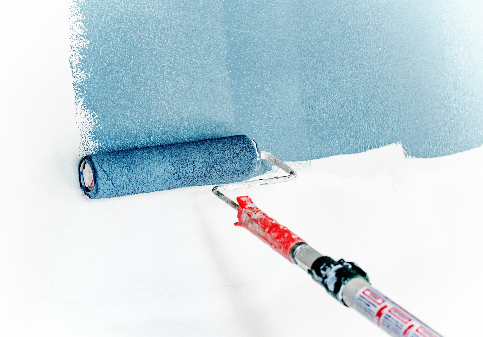 Paint roller, rolling blue paint on wall